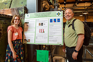 A mentor and mentee stand in front of an academic poster.